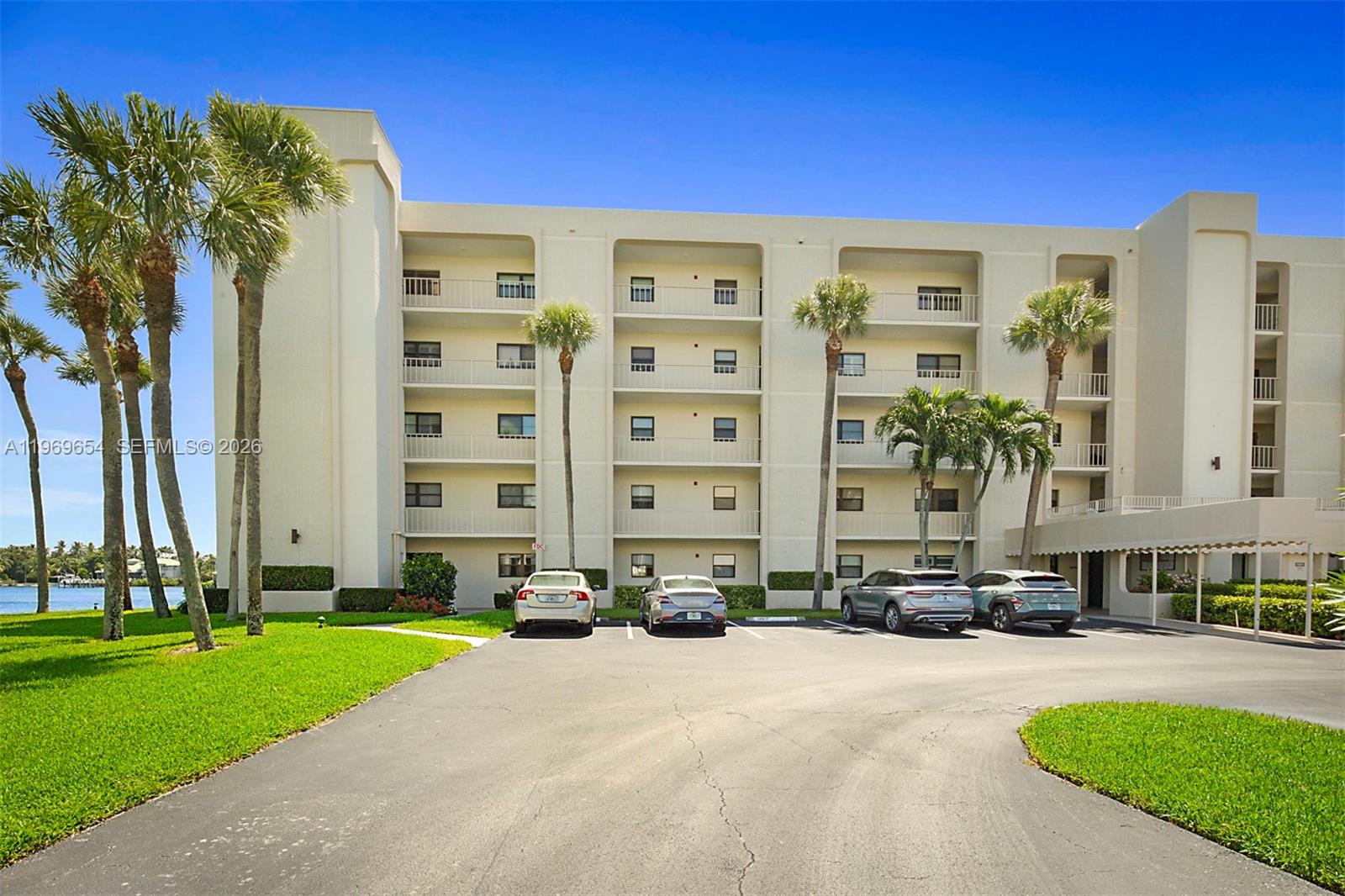 A multi-story apartment building with a parking lot and palm trees in front — 100 Intracoastal Pl # 102, Jupiter FL 33469, JUPITER, FL