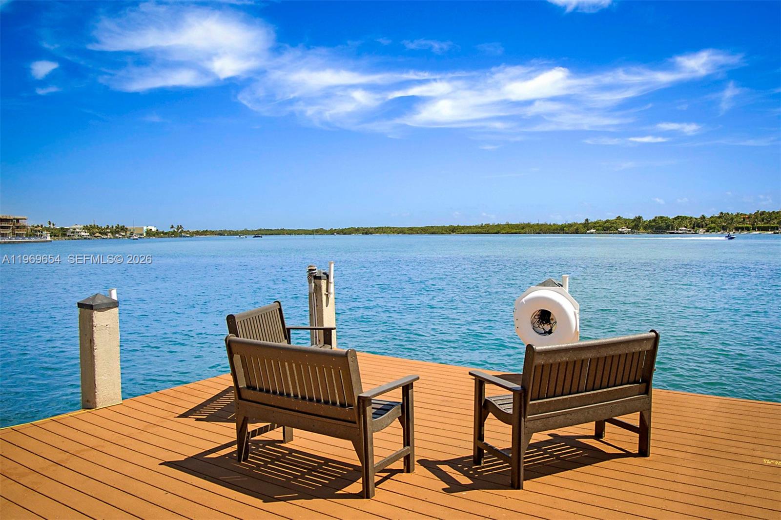 A wooden dock with two benches overlooks a calm blue bay under a sunny sky — 100 Intracoastal Pl # 102, Jupiter FL 33469, JUPITER, FL