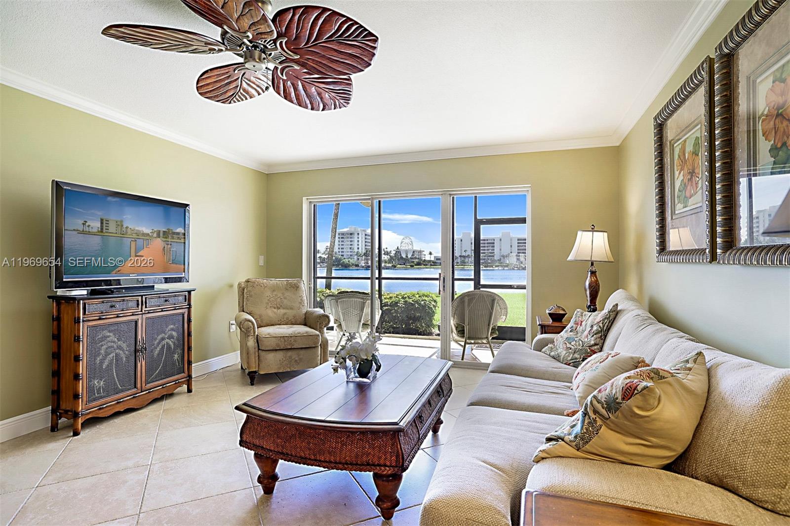A living room features a palm-leaf ceiling fan, tile floors, and a view of water — 100 Intracoastal Pl # 102, Jupiter FL 33469, JUPITER, FL