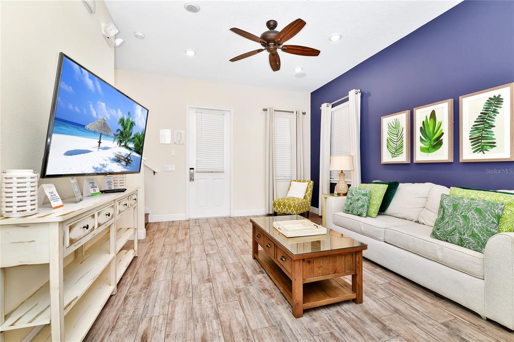 A living room features a white sofa, a wooden coffee table, and a navy accent wall — 8048 DREAMSICLE DRIVE, KISSIMMEE, FL