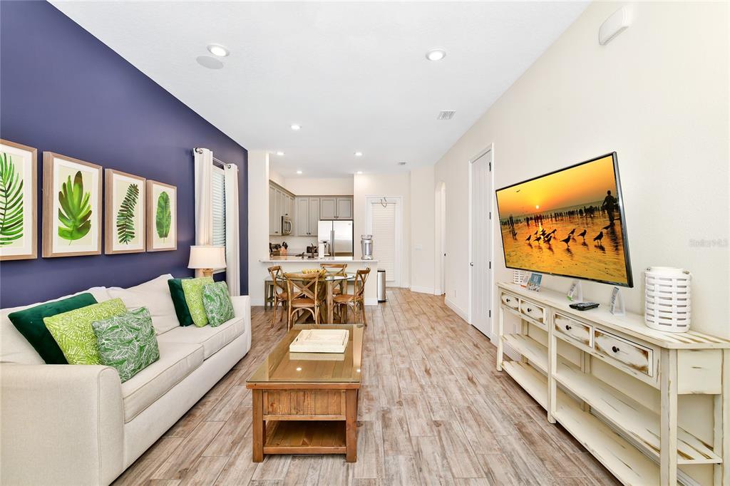 A living room with a dark blue accent wall, white sofa, and wood-look tile flooring — 8048 DREAMSICLE DRIVE, KISSIMMEE, FL