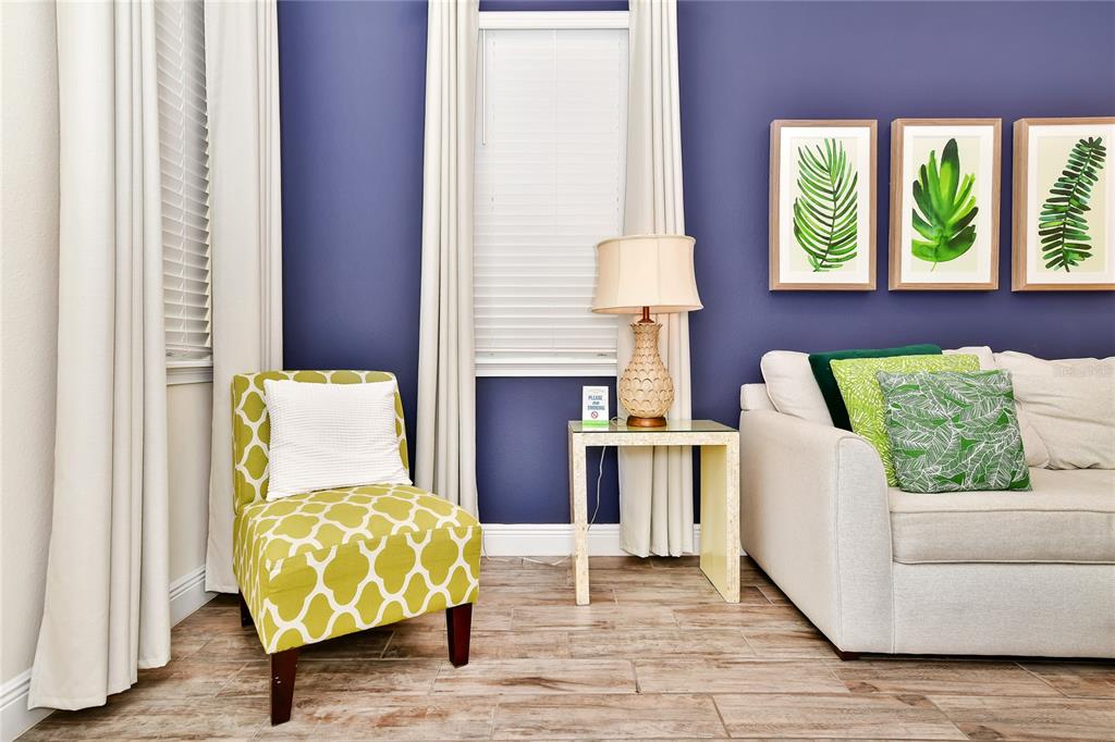 A living room features a dark blue accent wall, a light sofa, and patterned green chairs — 8048 DREAMSICLE DRIVE, KISSIMMEE, FL