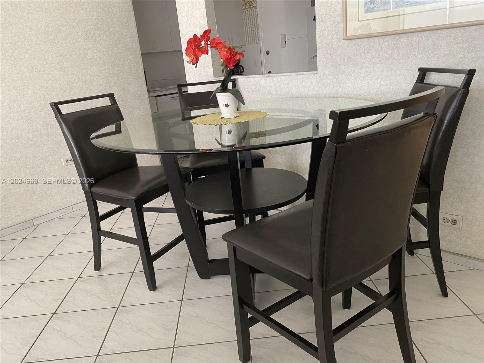 A glass-topped dining table with four dark chairs sits on a tiled floor — 3505 S Ocean Dr # 704, Hollywood FL 33019, HOLLYWOOD, FL