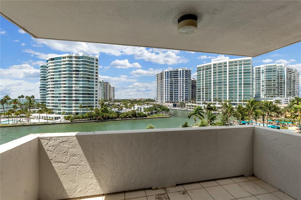 A balcony with tiled flooring overlooks a canal and several high-rise apartment buildings — 101 SUNSET DRIVE UNIT PH1, SARASOTA, FL