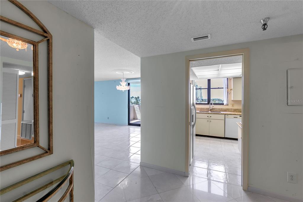 A view from a hallway looking into a kitchen and an adjacent living area — 101 SUNSET DRIVE UNIT PH1, SARASOTA, FL