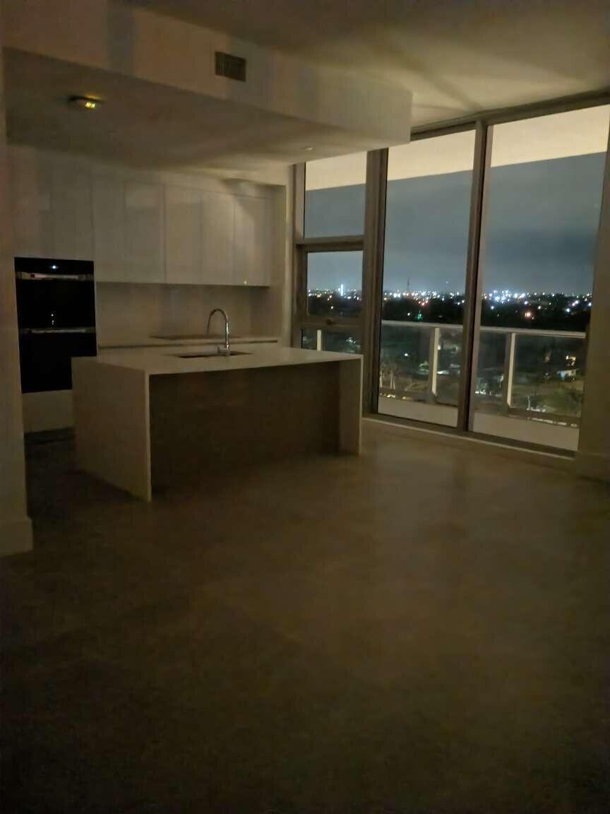 A modern kitchen with a waterfall island and floor-to-ceiling windows overlooking a city at night — 220 Lake Shore Drive # 823, FL 33403, FL