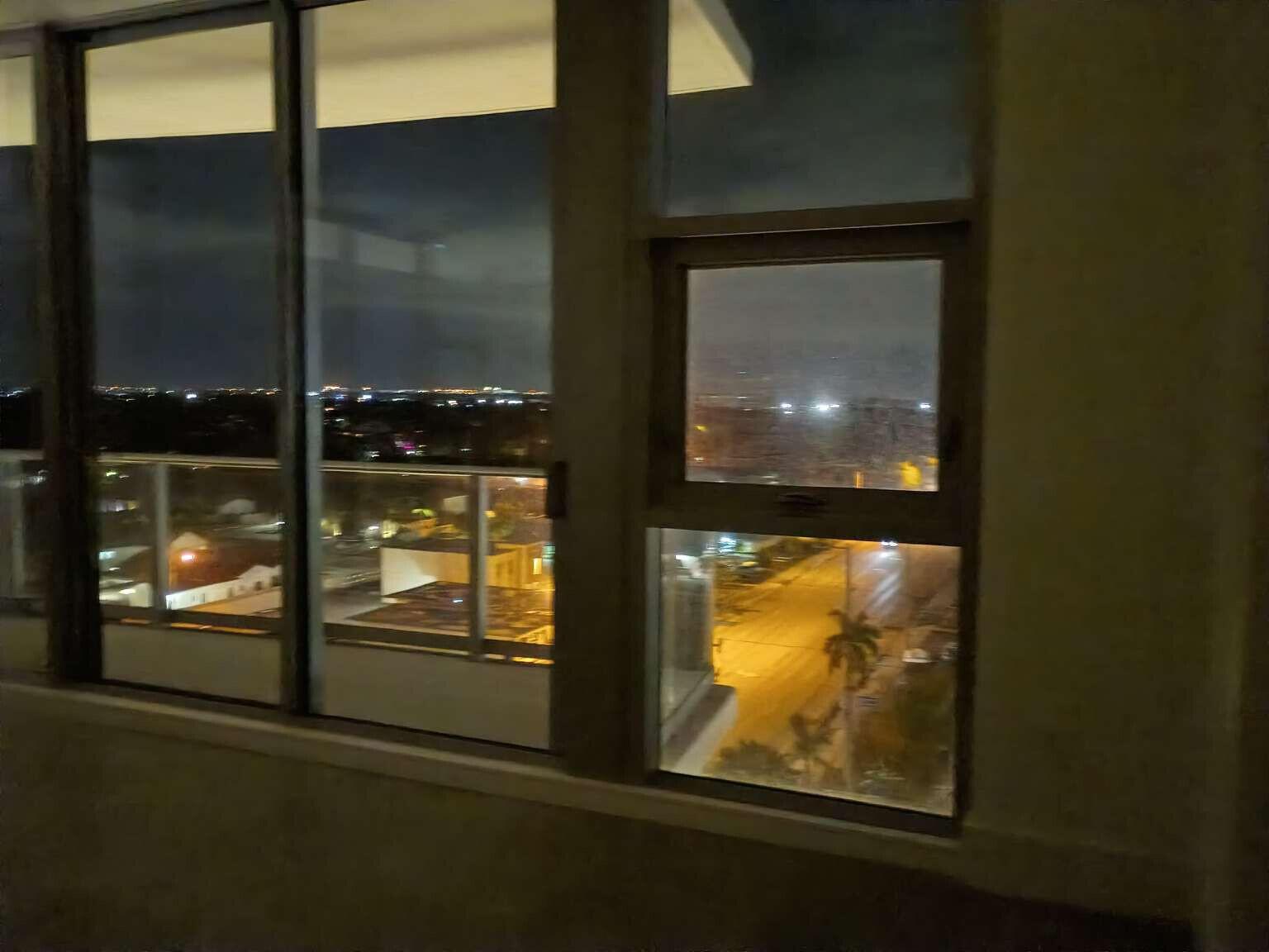 A view of a city street at night through large, floor-to-ceiling apartment windows — 220 Lake Shore Drive # 823, FL 33403, FL