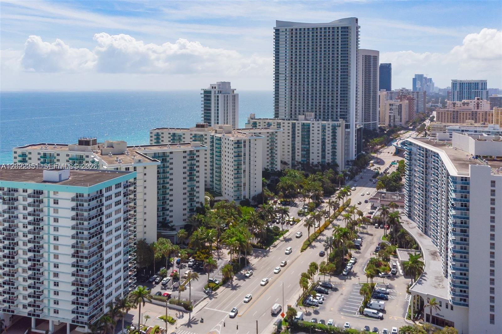 An aerial view shows high-rise apartment buildings along a coastal road with palm trees — 3801 S Ocean Dr # 2Z, Hollywood FL 33019, HOLLYWOOD, FL