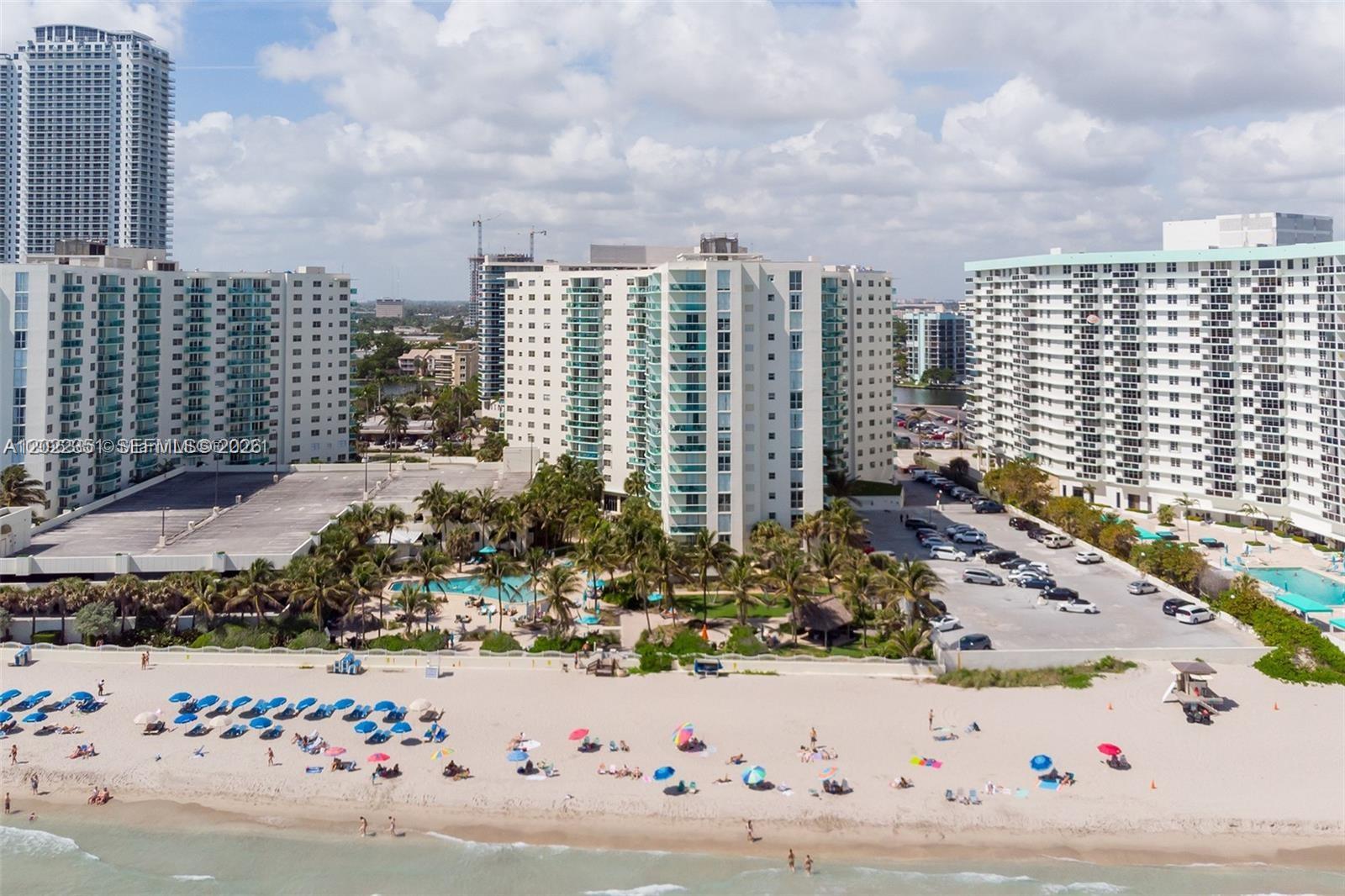 An aerial view shows high-rise apartment buildings situated directly behind a sandy beach — 3801 S Ocean Dr # 2Z, Hollywood FL 33019, HOLLYWOOD, FL
