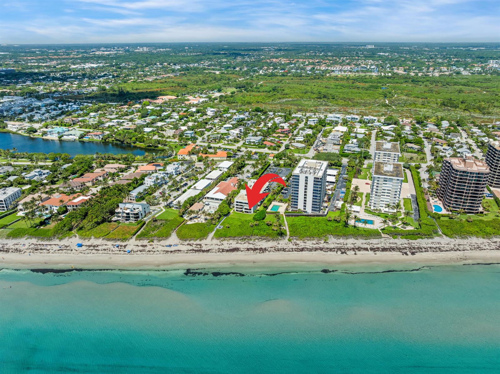 An aerial view shows a beachfront condominium building marked by a red arrow — 420 Celestial Way # 205, Juno Beach FL 33408, JUNO BEACH, FL