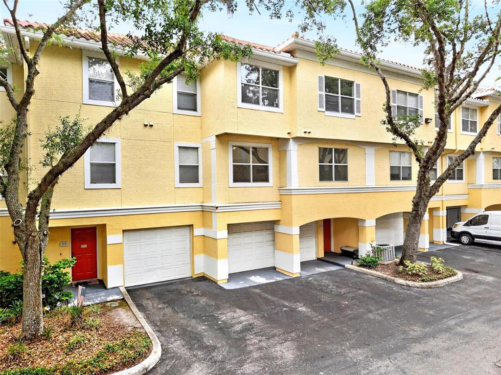 A three-story yellow townhouse complex features multiple garage doors and a paved driveway — 2847 SHADOW VIEW CIRCLE UNIT 2847, MAITLAND, FL