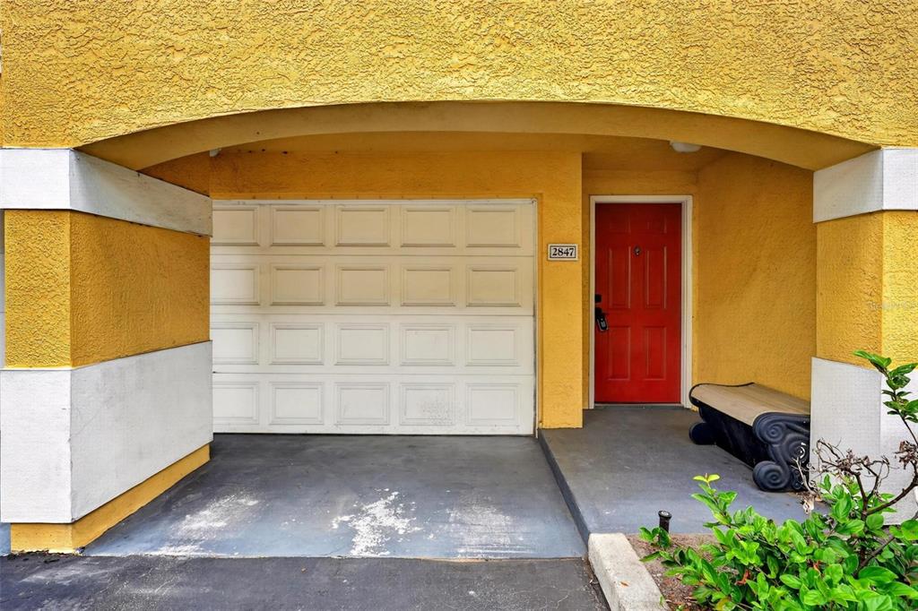 A yellow stucco building exterior features a white garage door and a red front door — 2847 SHADOW VIEW CIRCLE UNIT 2847, MAITLAND, FL