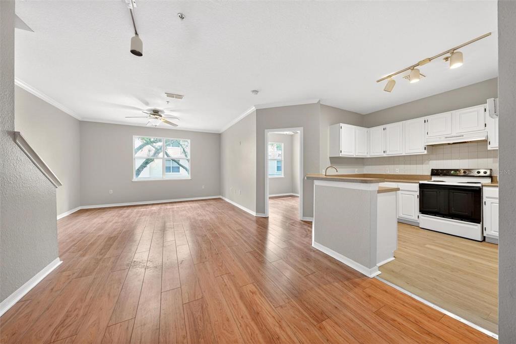 An open-concept living area features wood-look flooring, a kitchen with white cabinets, and a staircase — 2847 SHADOW VIEW CIRCLE UNIT 2847, MAITLAND, FL