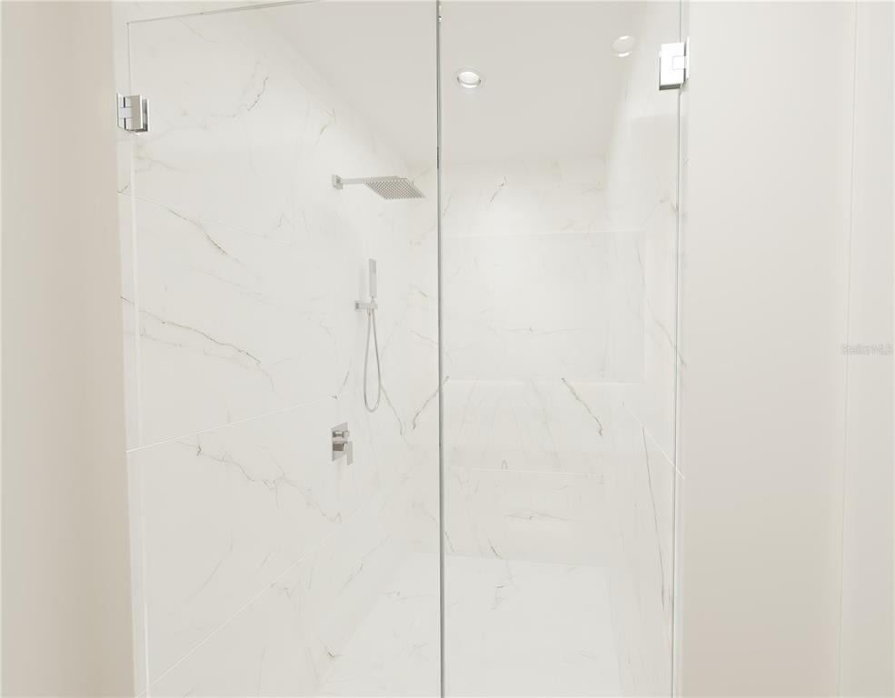 A walk-in shower features white marble-look tile walls, a glass door, and chrome fixtures — 4950 REMINGTON DRIVE UNIT 302, SARASOTA, FL