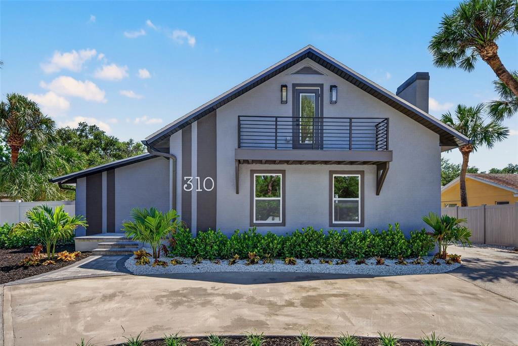A two-story gray house with a balcony, dark trim, and a concrete driveway — 310 PARK STREET N, ST PETERSBURG, FL