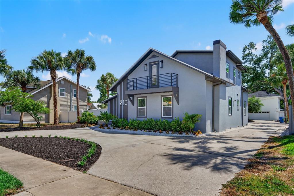 A two-story gray house with a balcony, a concrete driveway, and palm trees — 310 PARK STREET N, ST PETERSBURG, FL