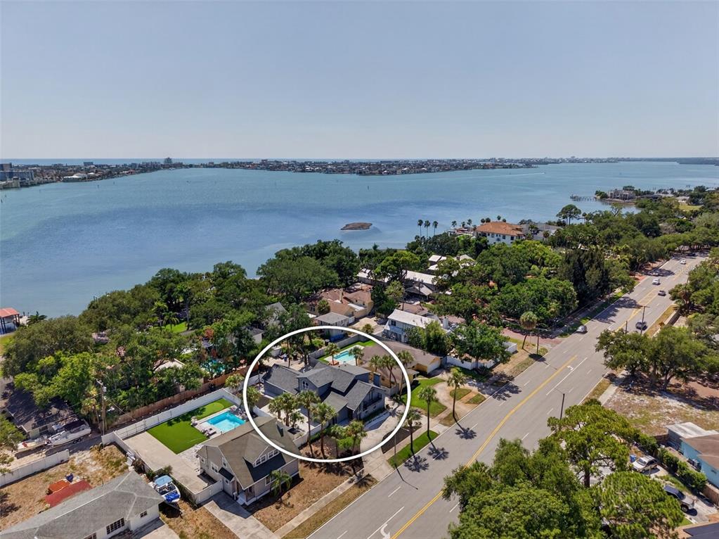 An aerial view shows a house with a pool surrounded by trees near a bay — 310 PARK STREET N, ST PETERSBURG, FL