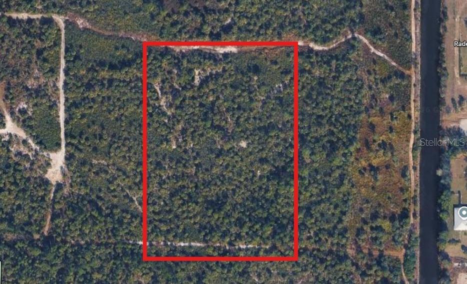 An aerial view shows a rectangular, wooded plot of land outlined in red — 2000 WOODLAND GRADE ROAD, NAPLES, FL
