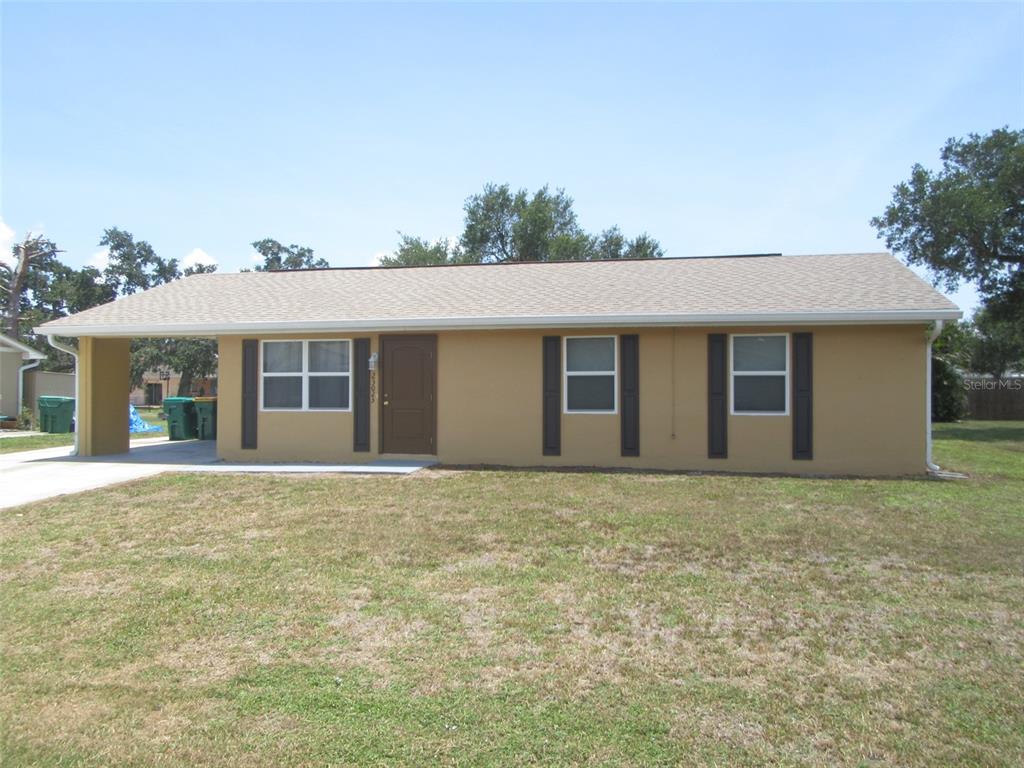 A single-story house with a tan exterior, dark shutters, and a covered carport — 23023 FOOTE AVENUE, PORT CHARLOTTE, FL