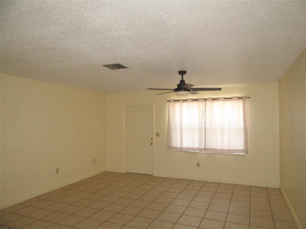 An empty room features light-colored walls, tiled flooring, a ceiling fan, and a window — 23023 FOOTE AVENUE, PORT CHARLOTTE, FL