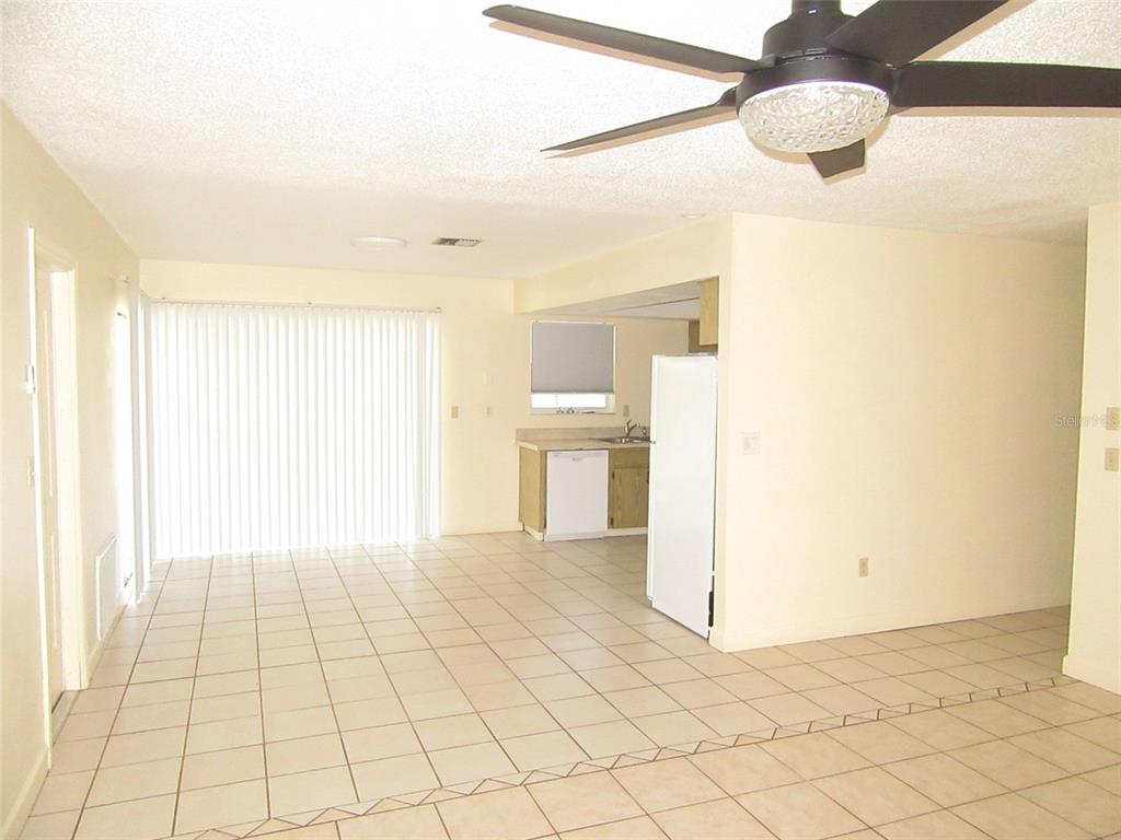 An open-concept living and dining area features light tile flooring and a ceiling fan — 23023 FOOTE AVENUE, PORT CHARLOTTE, FL