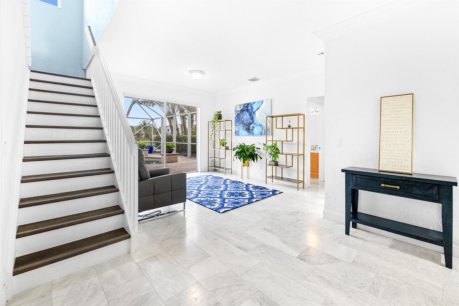A bright living area features marble floors, a staircase, and a view of a pool — 6575 Spring Meadow Drive, FL 33413, FL