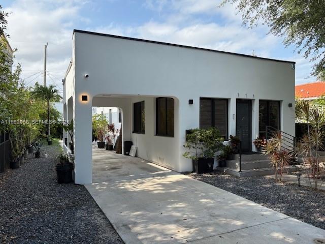A white, flat-roofed house features a large carport and a gravel driveway — 111 NW 46th St, Miami FL 33127, MIAMI, FL
