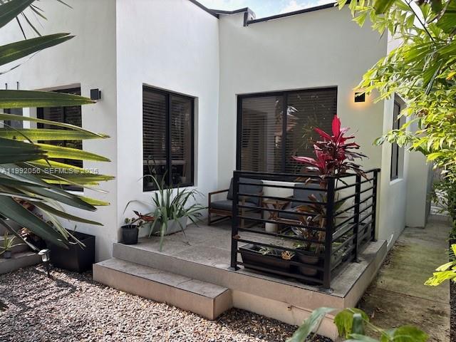 A white stucco house exterior features a small patio with a black metal railing — 111 NW 46th St, Miami FL 33127, MIAMI, FL