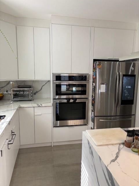 A modern kitchen features white cabinetry, stainless steel appliances, and marble-patterned countertops — 111 NW 46th St, Miami FL 33127, MIAMI, FL