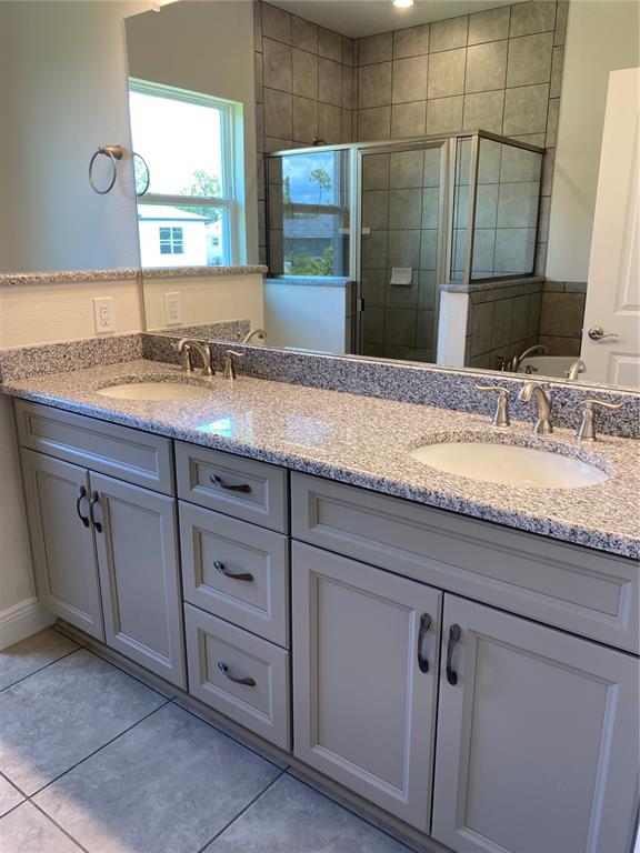 A bathroom features a double-sink granite vanity with gray cabinets and a tiled shower stall — 2139 GASCOM STREET, NORTH PORT, FL