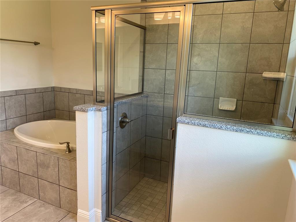 A bathroom features a tiled soaking tub and a glass-enclosed shower with gray tile walls — 2139 GASCOM STREET, NORTH PORT, FL