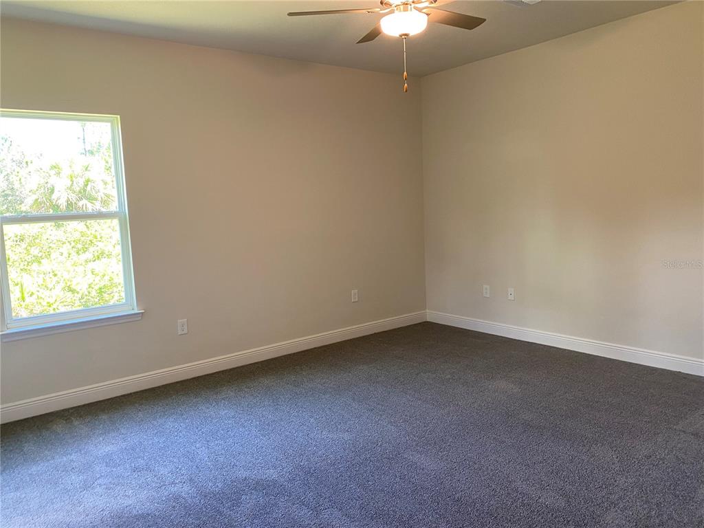 An empty bedroom features gray carpeting, beige walls, a ceiling fan, and a single window — 2139 GASCOM STREET, NORTH PORT, FL