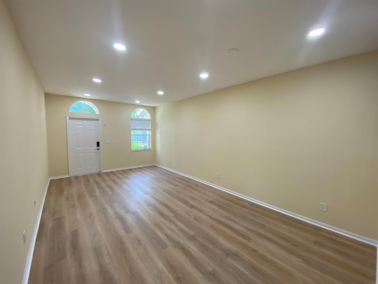 An empty room with light-colored walls, wood-look flooring, recessed lighting, and an arched entryway — 4456 Regal Court, Delray Beach FL 33445, DELRAY BEACH, FL