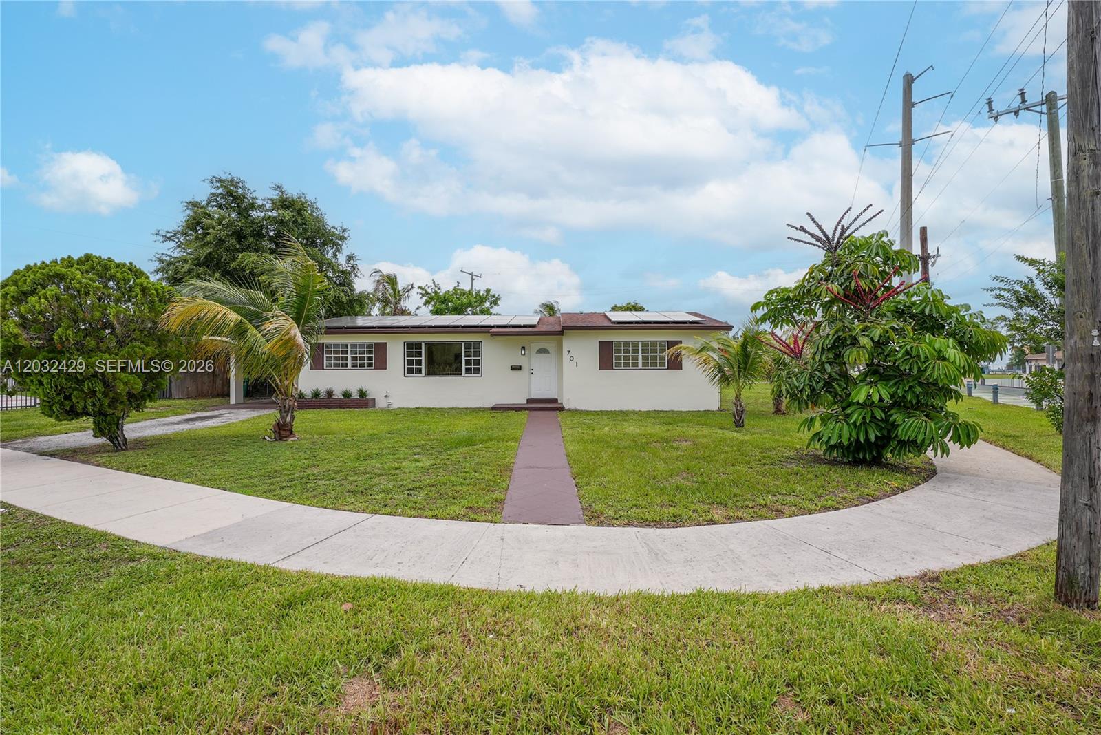 A single-story house with a white exterior, solar panels, and a front lawn — 701 NW 176th Ter, Miami Gardens FL 33169, MIAMI GARDENS, FL
