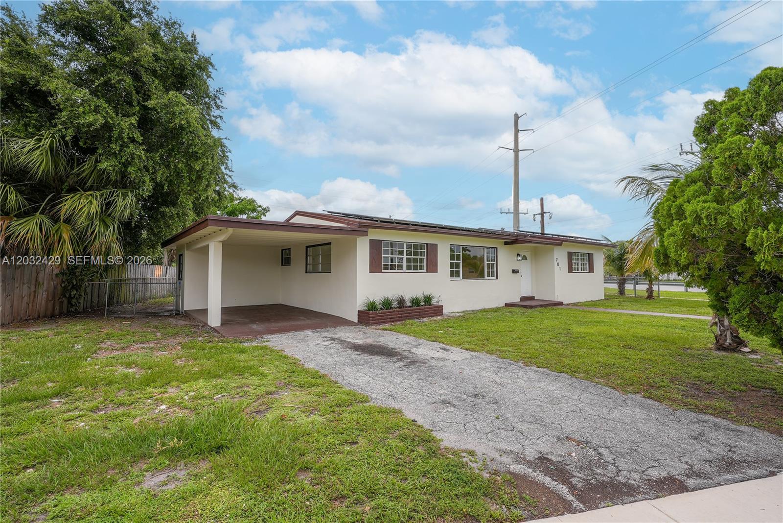 A single-story house with a carport, a gravel driveway, and a front lawn — 701 NW 176th Ter, Miami Gardens FL 33169, MIAMI GARDENS, FL