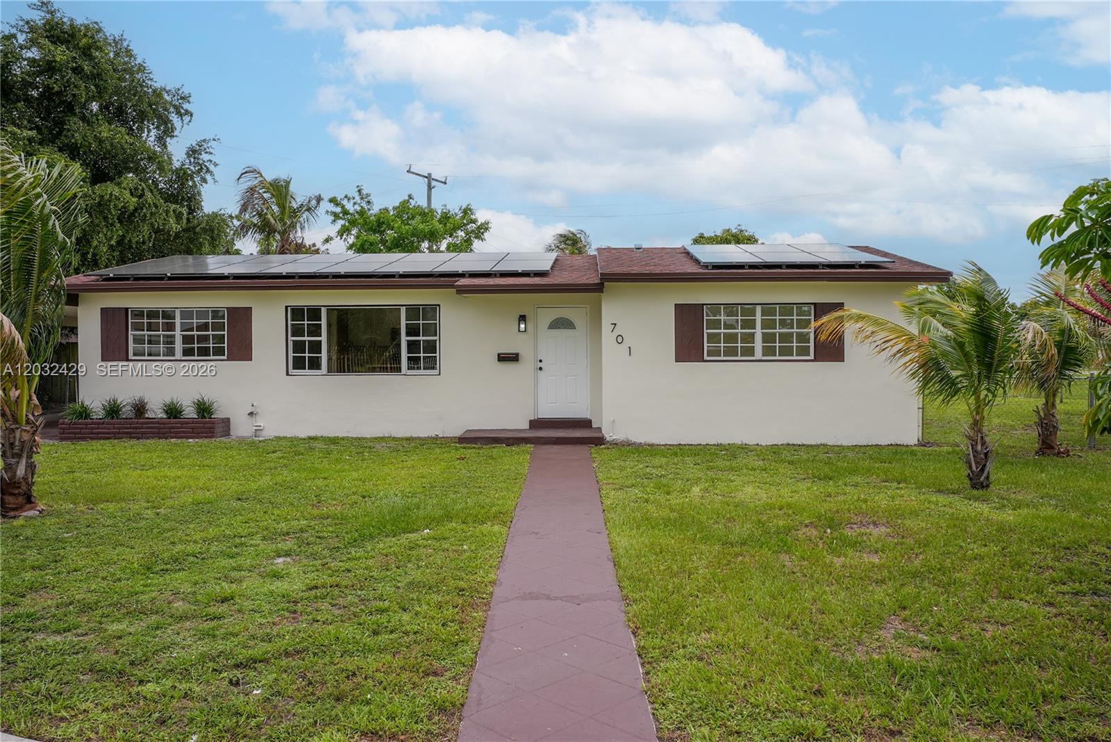 A single-story house with a white exterior, brown shutters, and solar panels on the roof — 701 NW 176th Ter, Miami Gardens FL 33169, MIAMI GARDENS, FL