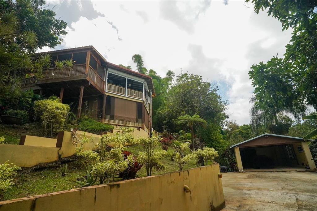 A two-story house with a wooden deck sits on a hillside above a detached garage — LOT 2 B URB VILLAS DE MONTE VERDE, PONCE, PR
