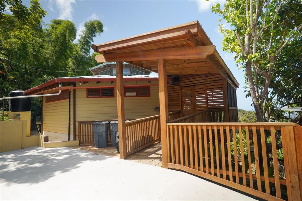 A wooden ramp leads to the entrance of a yellow house with a covered porch — LOT 2 B URB VILLAS DE MONTE VERDE, PONCE, PR