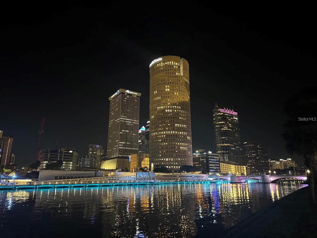 A night view of the Tampa skyline featuring the cylindrical Rivergate Tower reflected in water — 724 CORAL REEF DRIVE, TAMPA, FL