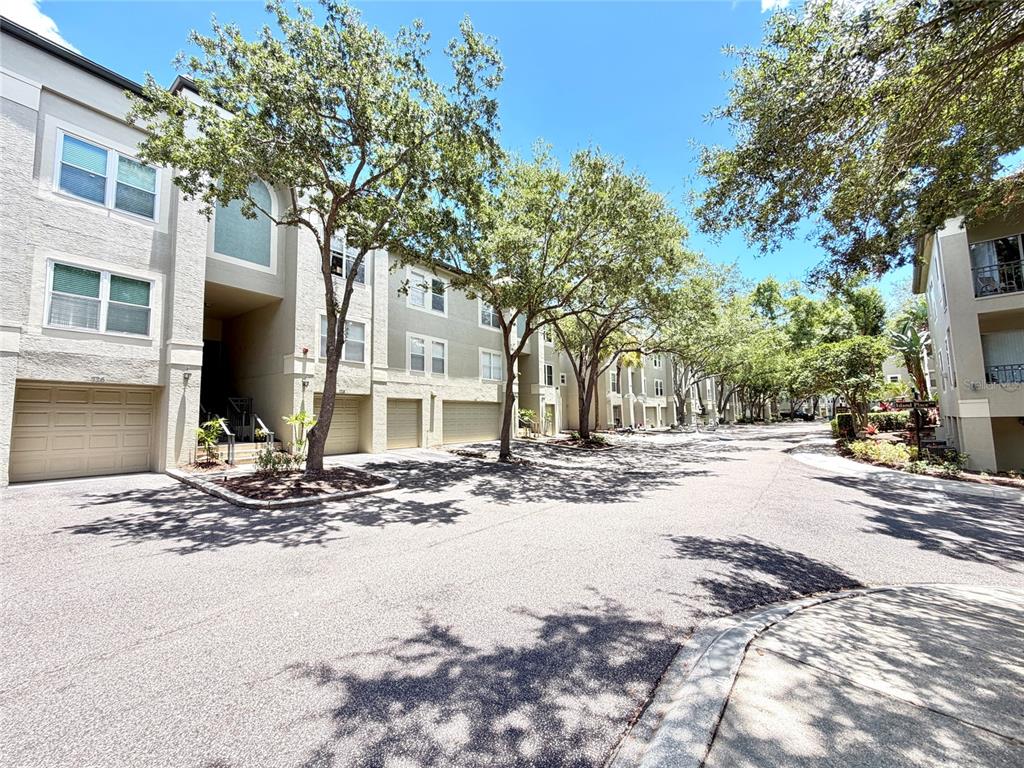 A street view of multi-story residential townhomes with attached garages and mature trees — 724 CORAL REEF DRIVE, TAMPA, FL