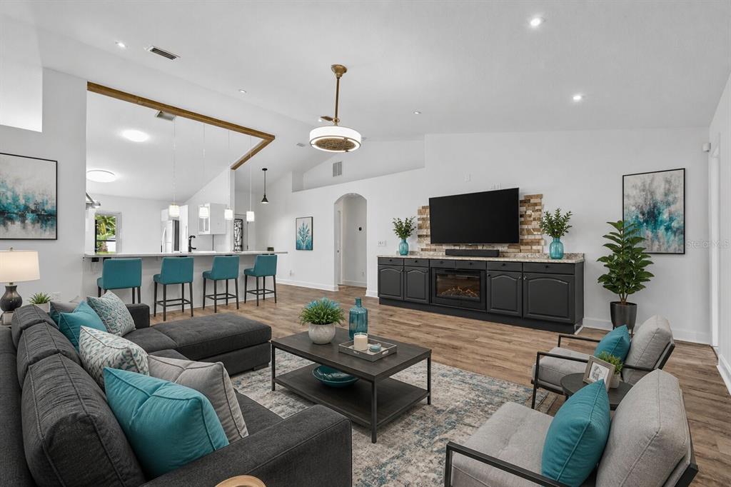 A living room with a sectional sofa, two armchairs, a fireplace, and an open kitchen — 23 ESSINGTON LANE, PALM COAST, FL