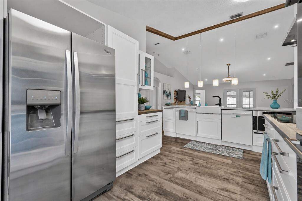 A modern kitchen features white cabinetry, stainless steel appliances, and wood-look flooring — 23 ESSINGTON LANE, PALM COAST, FL