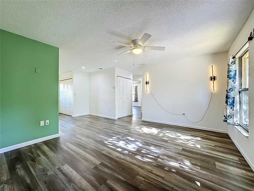 A living room features wood-look flooring, a green accent wall, and two wall-mounted light fixtures — 2006 7TH AVENUE W UNIT B, BRADENTON, FL