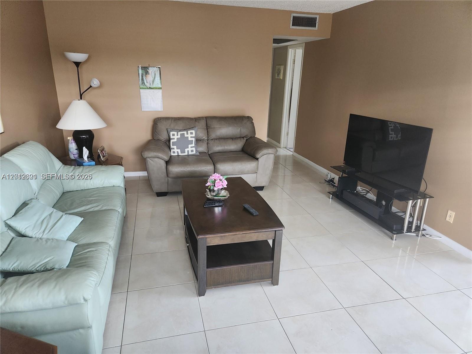 A living room features a light green sofa, a grey loveseat, and a television console — DEERFIELD BEACH, FL