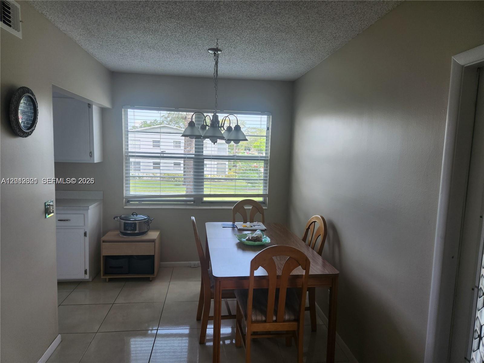 A dining area features a wooden table, four chairs, a light fixture, and tile flooring — DEERFIELD BEACH, FL