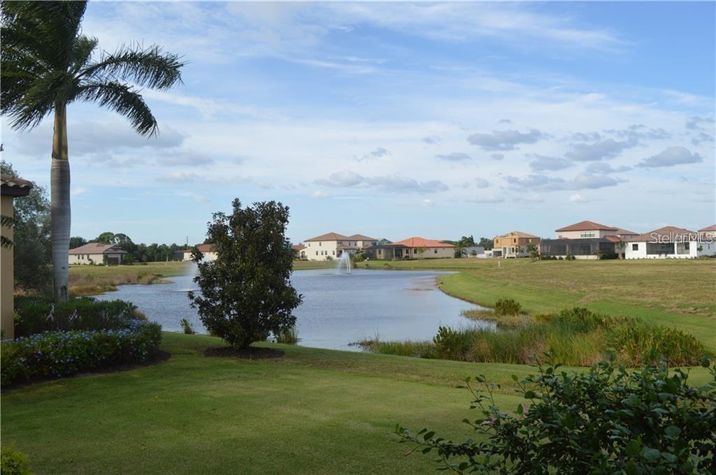 A view of a pond with fountains, surrounded by grassy lawns and suburban houses — 5815 INSPIRATION TERRACE, BRADENTON, FL