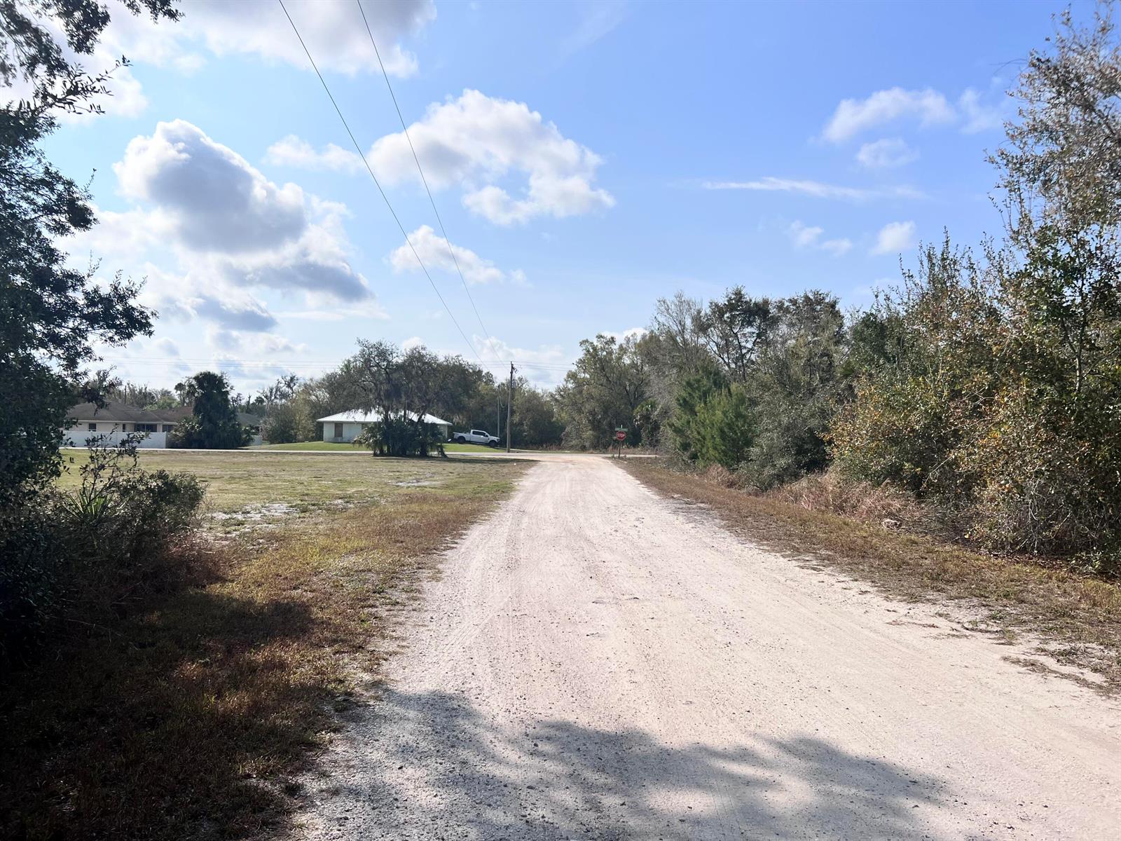 A dirt road leads toward a house in the distance under a blue sky — 4847 Brockton Avenue, FL 33875, FL