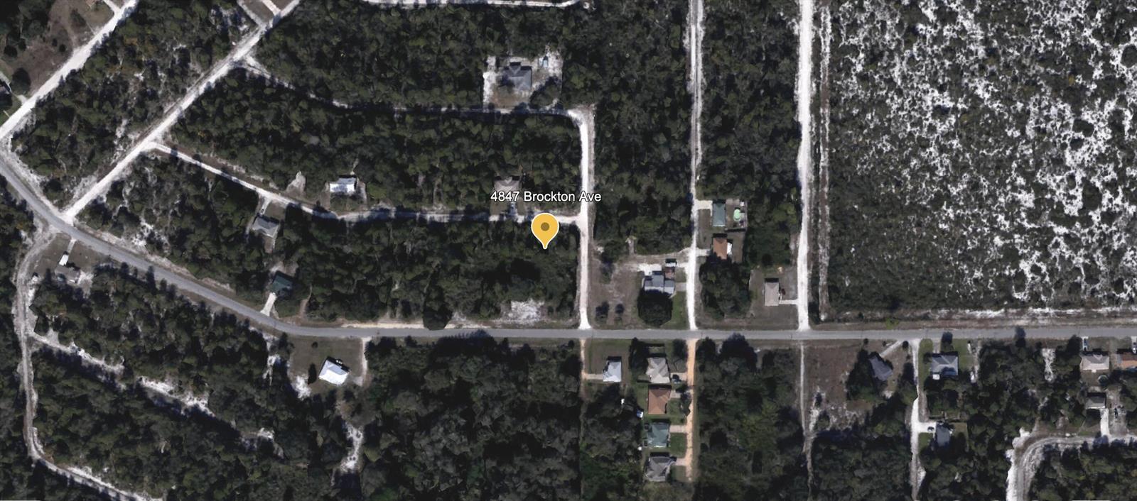 This is a satellite map view of a residential property surrounded by wooded land — 4847 Brockton Avenue, FL 33875, FL