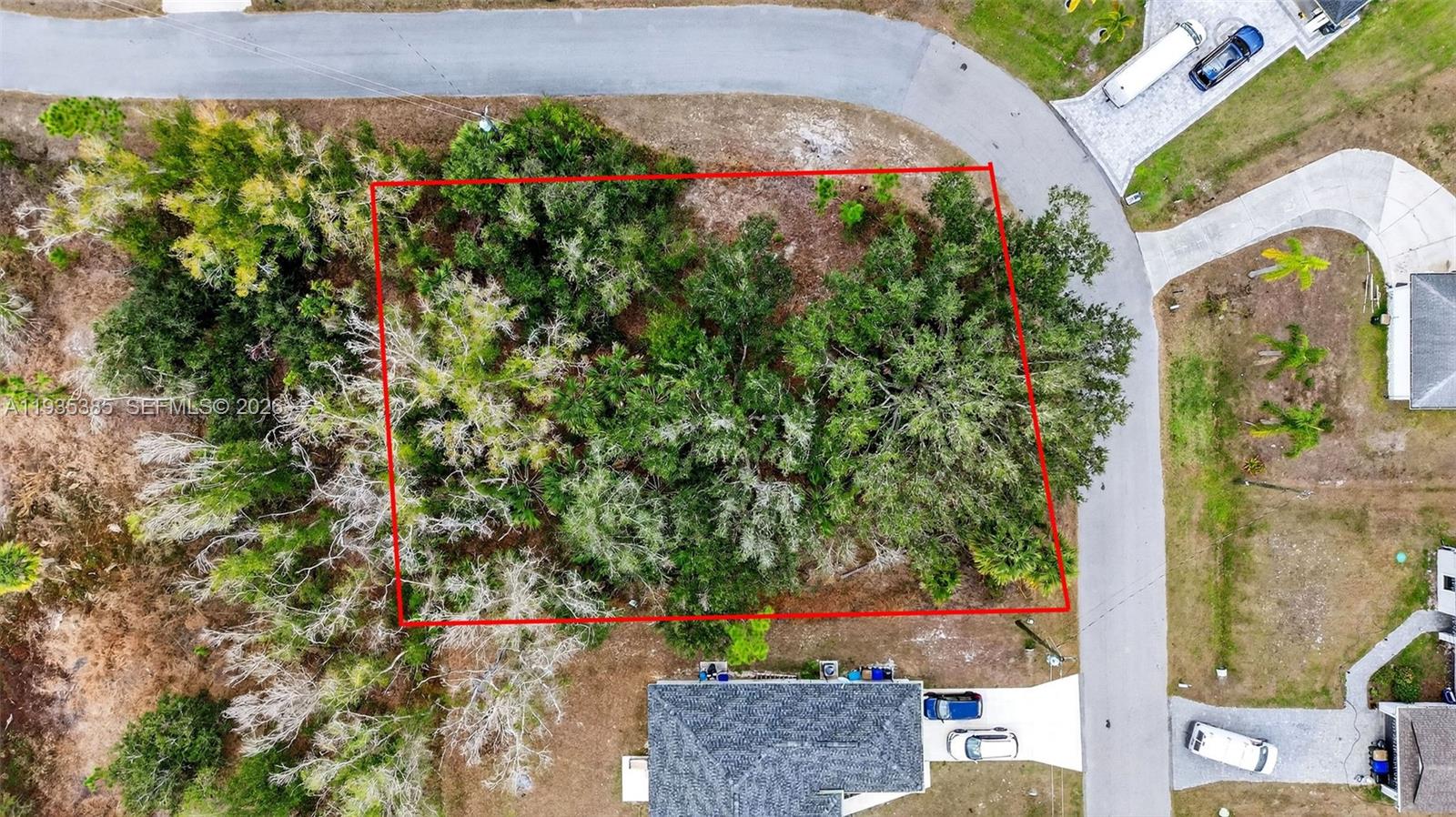 An aerial view shows a rectangular, tree-covered vacant lot outlined in red next to a road — 0 NELL RD, North Port FL 34288, NORTH PORT, FL