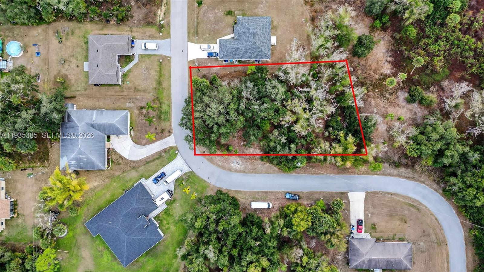 An aerial view shows a vacant, wooded residential lot outlined in red next to houses — 0 NELL RD, North Port FL 34288, NORTH PORT, FL